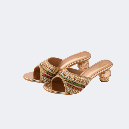 Gold embellished high-heeled sandals on a light gray background | Vogelle