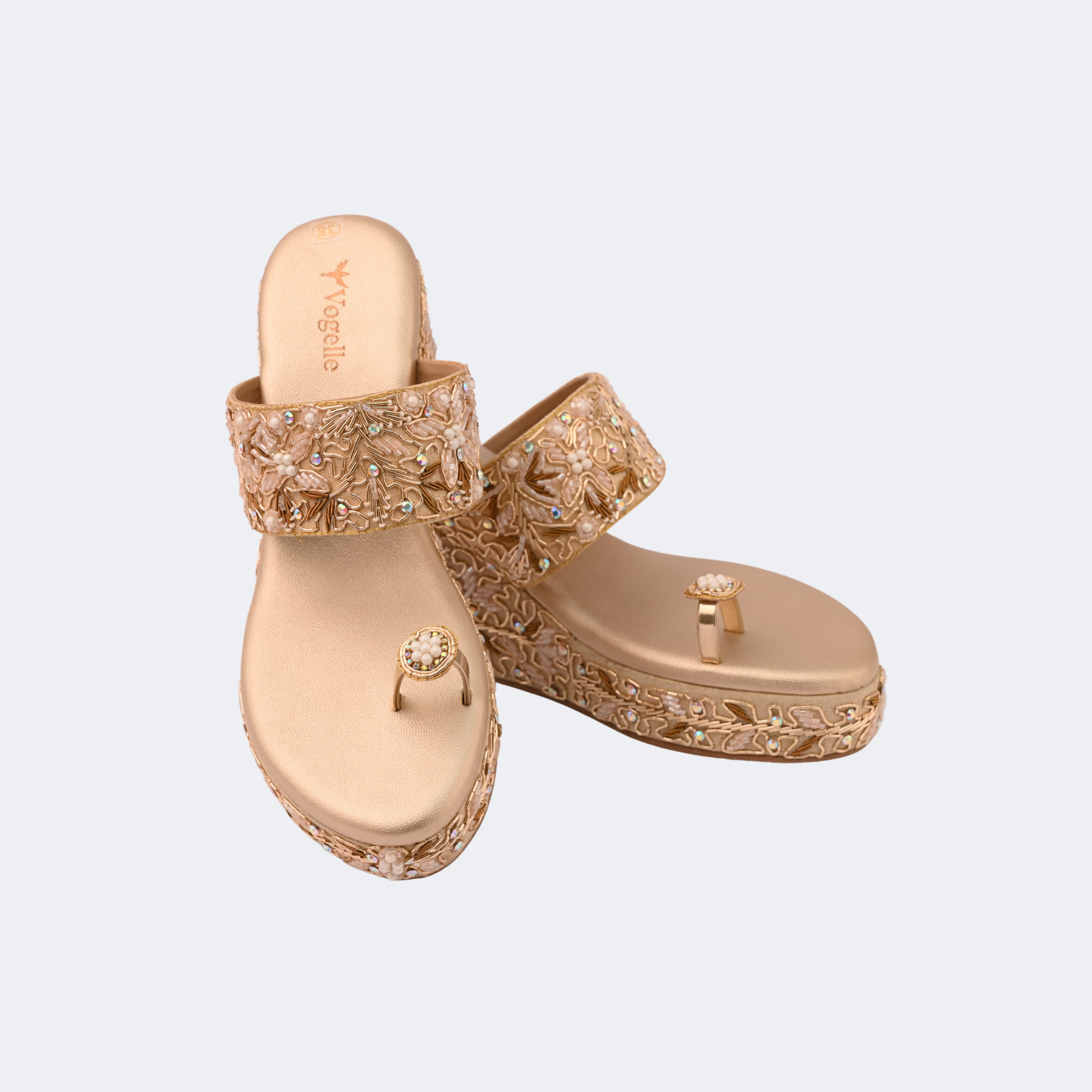 Pair of gold sandals with intricate designs on a light gray background