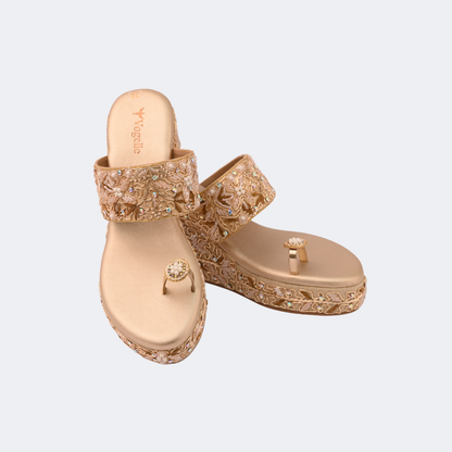 Pair of gold sandals with intricate designs on a light gray background