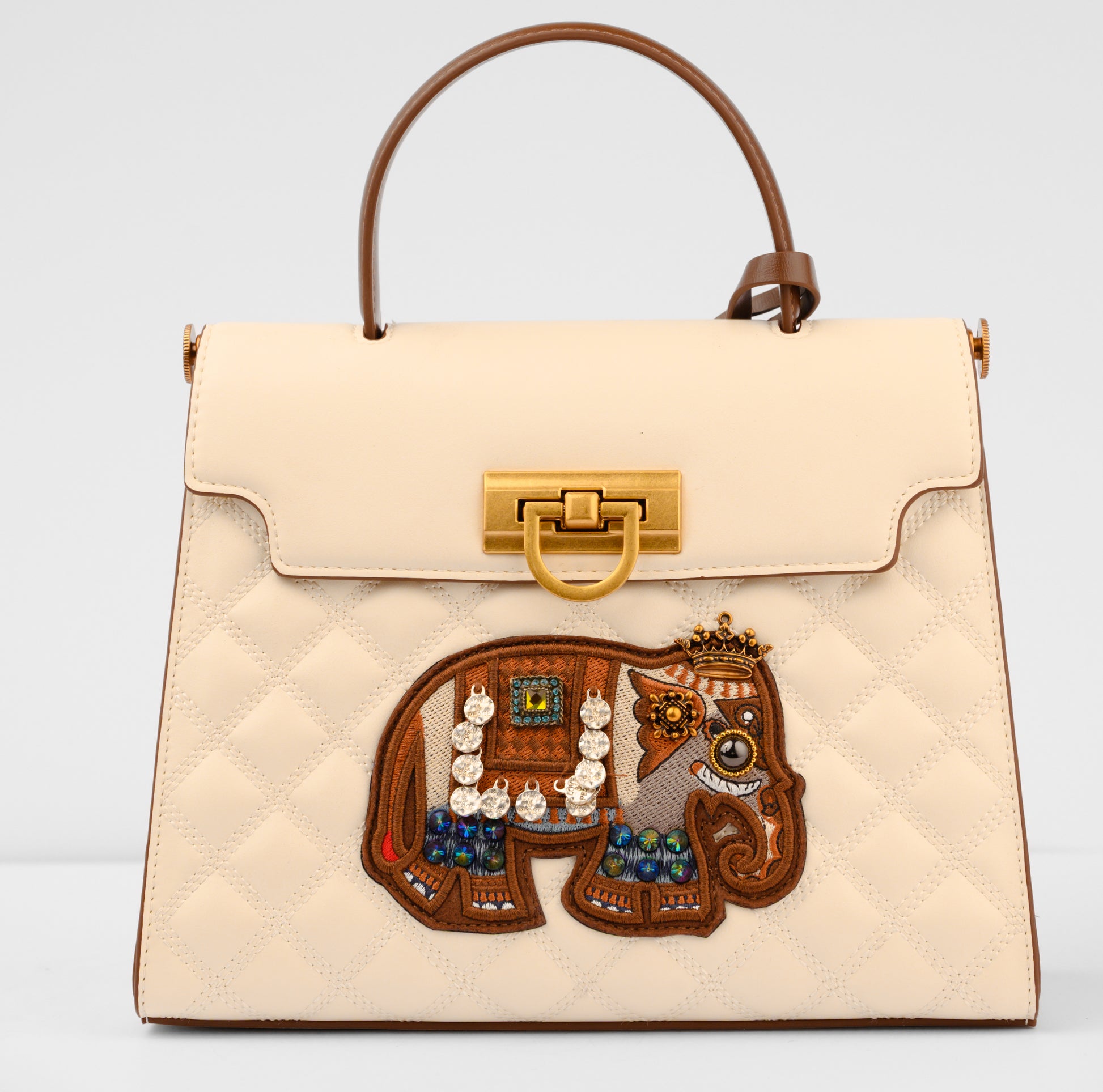 Beige handbag with a decorative lion emblem featuring jewelry on a light gray background | Vogelle