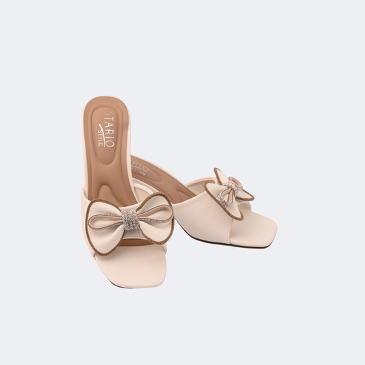 Beige high-heeled shoes with bow details on a light gray background | Vogelle
