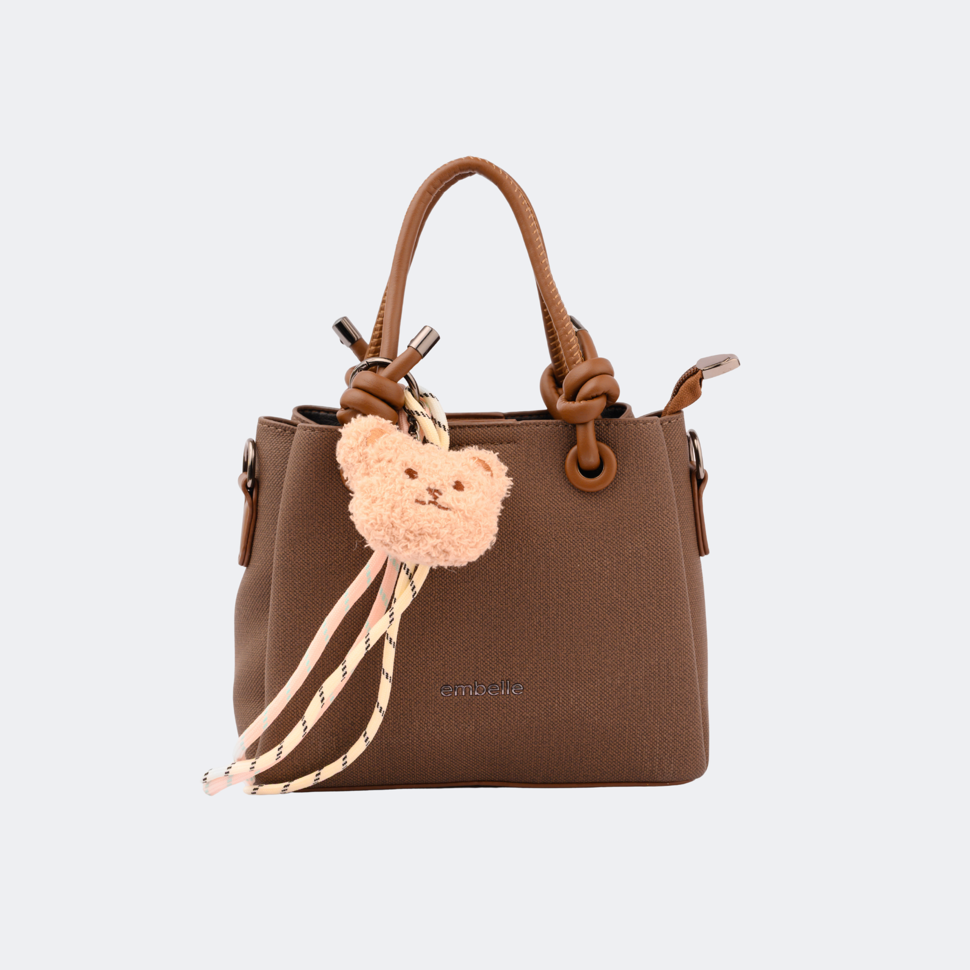 Brown handbag with a teddy bear keychain on a light gray background | Vogelle