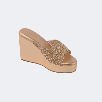 Gold wedge sandal with glittery strap on a light gray background | Vogelle