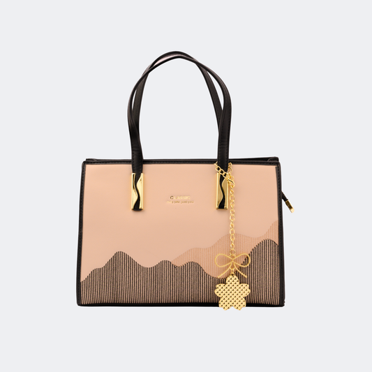 Handbag with black and beige design and gold charm on a light gray |background | Vogelle
