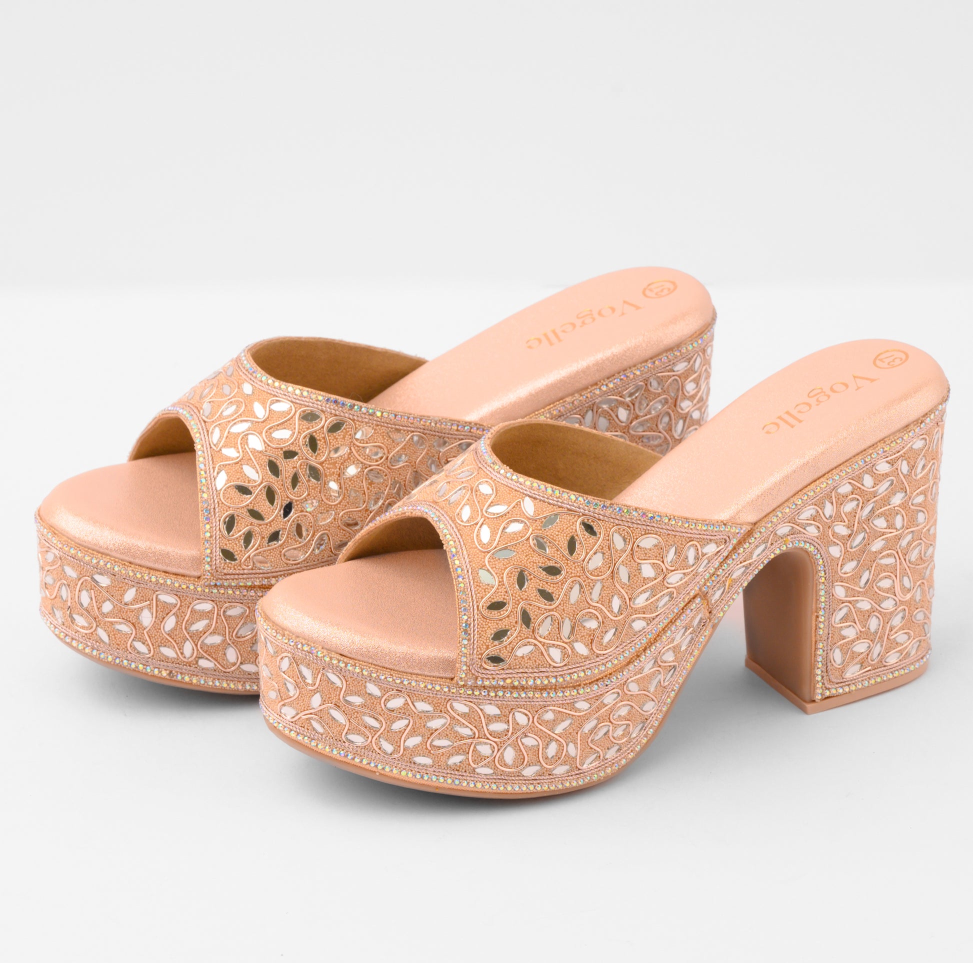 Pair of beige high-heeled sandals with intricate laser-cut design on a light gray background | Vogelle