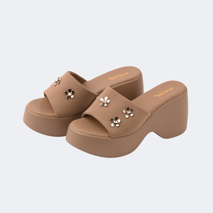 Pair of brown platform sandals with floral embellishments on a light gray background | Vogelle