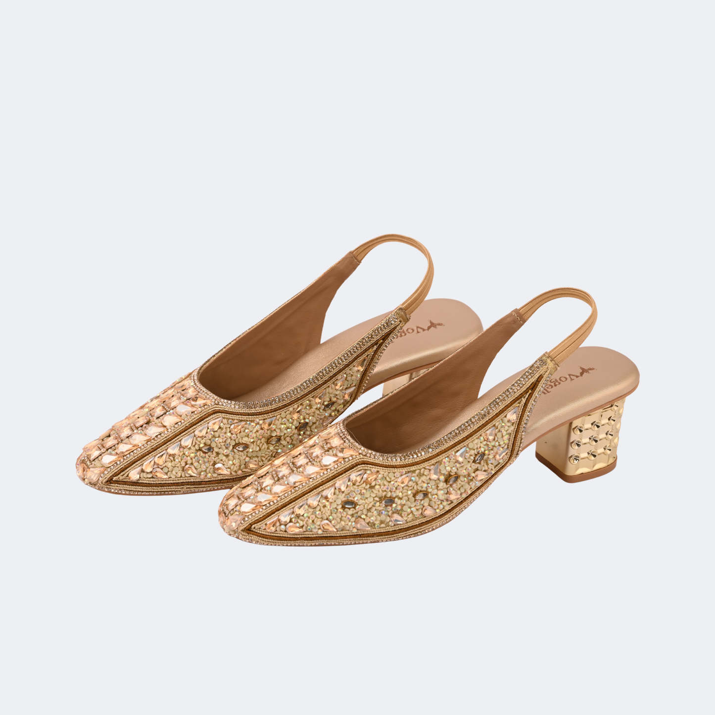 Pair of gold glittery high-heeled shoes on a light gray background | Vogelle