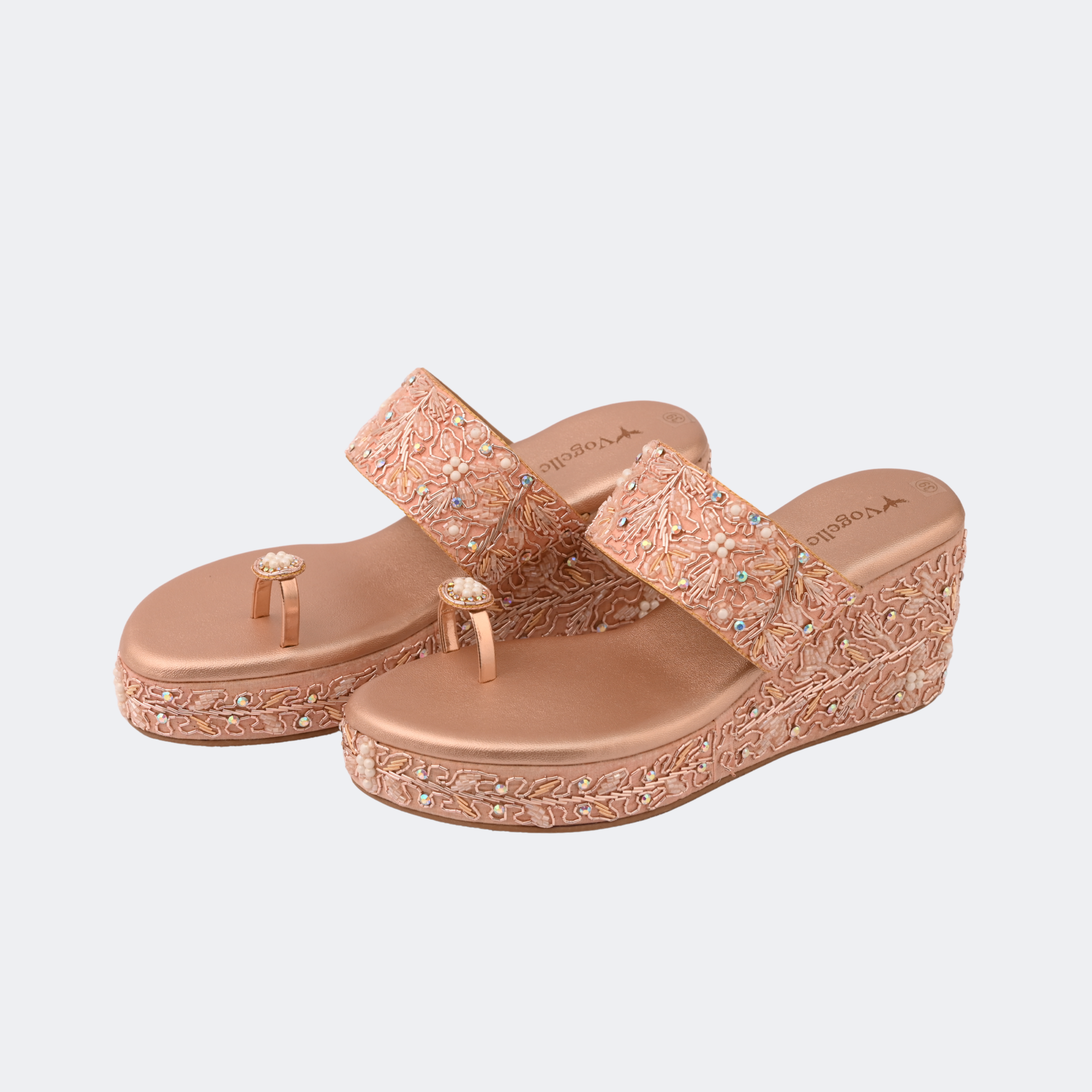 Pair of rose gold wedge sandals with decorative straps on a light gray background | Vogelle