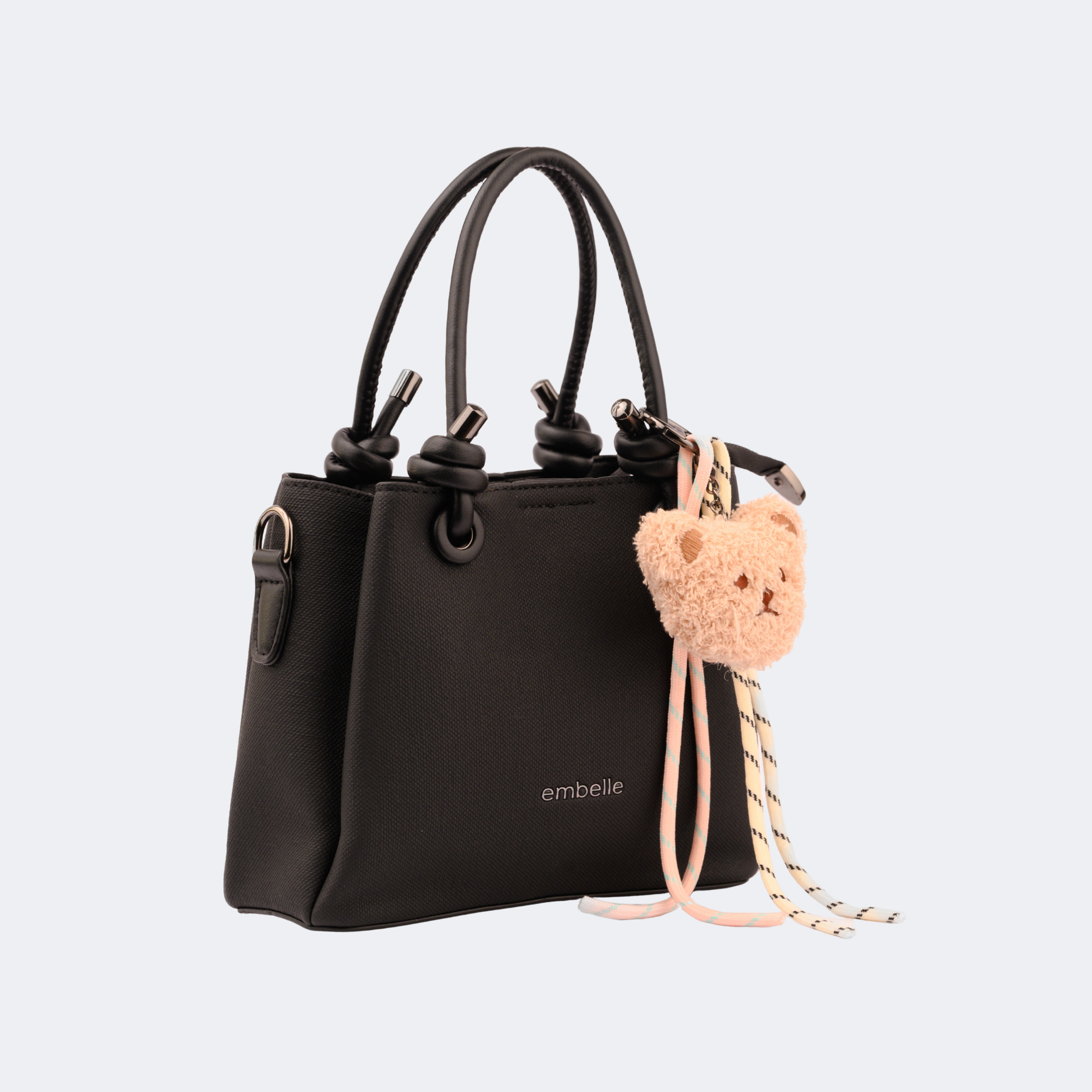 Black handbag with a teddy bear keychain on a light gray background | Vogelle